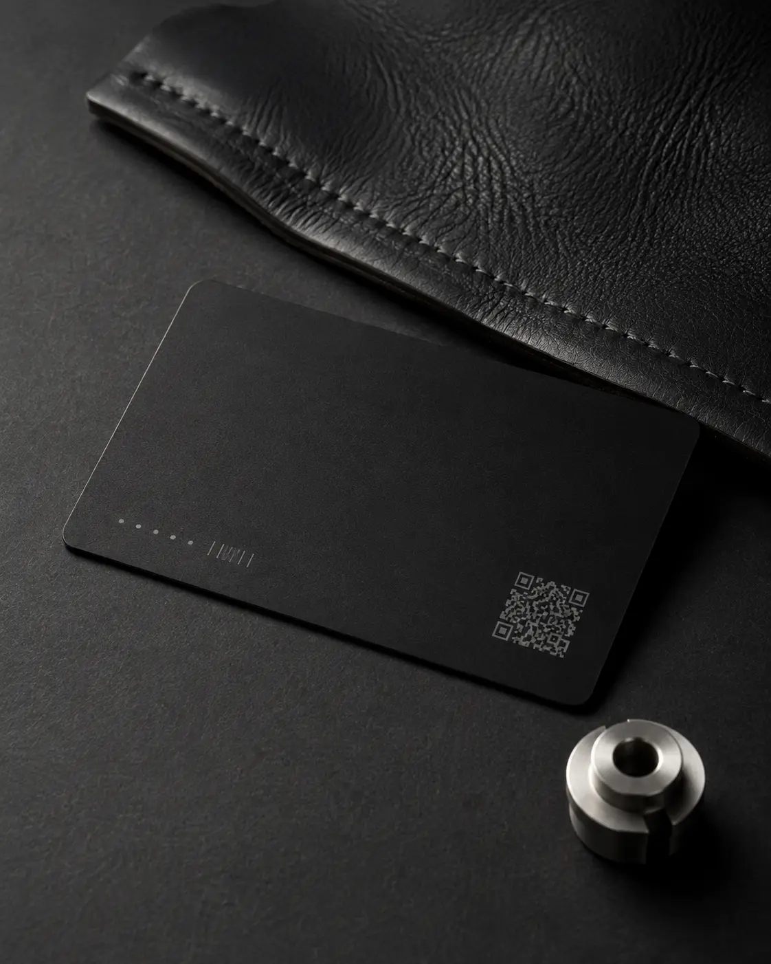 A thin black physical identity card presented with leather and precision metal components